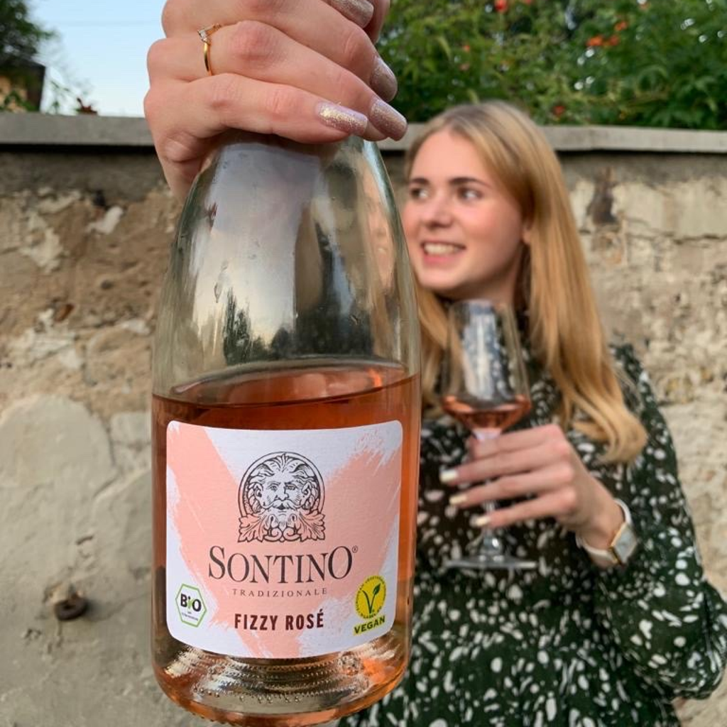 Junge Frau hält SONTINO BioVegan Fizzy Rosé Trocken 0,75l in der Hand 
